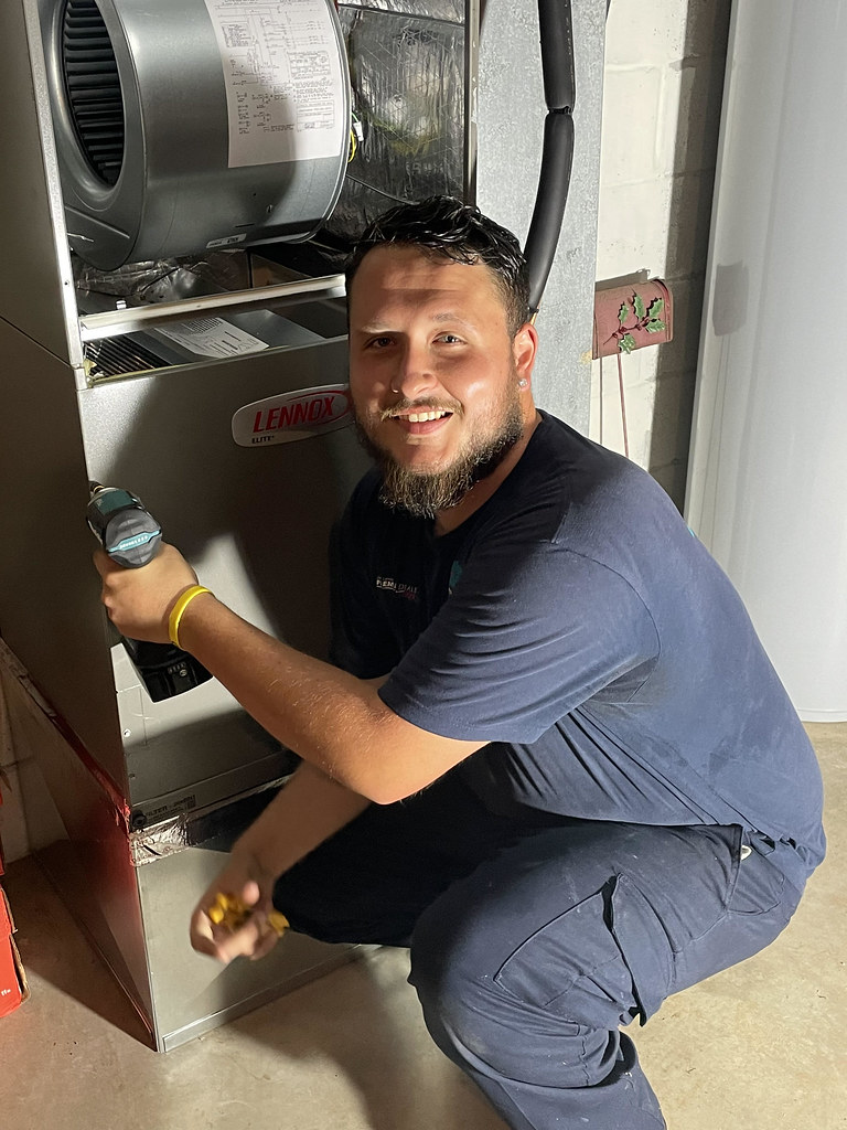 Technician fitting an air handler unit during a heat pump installation