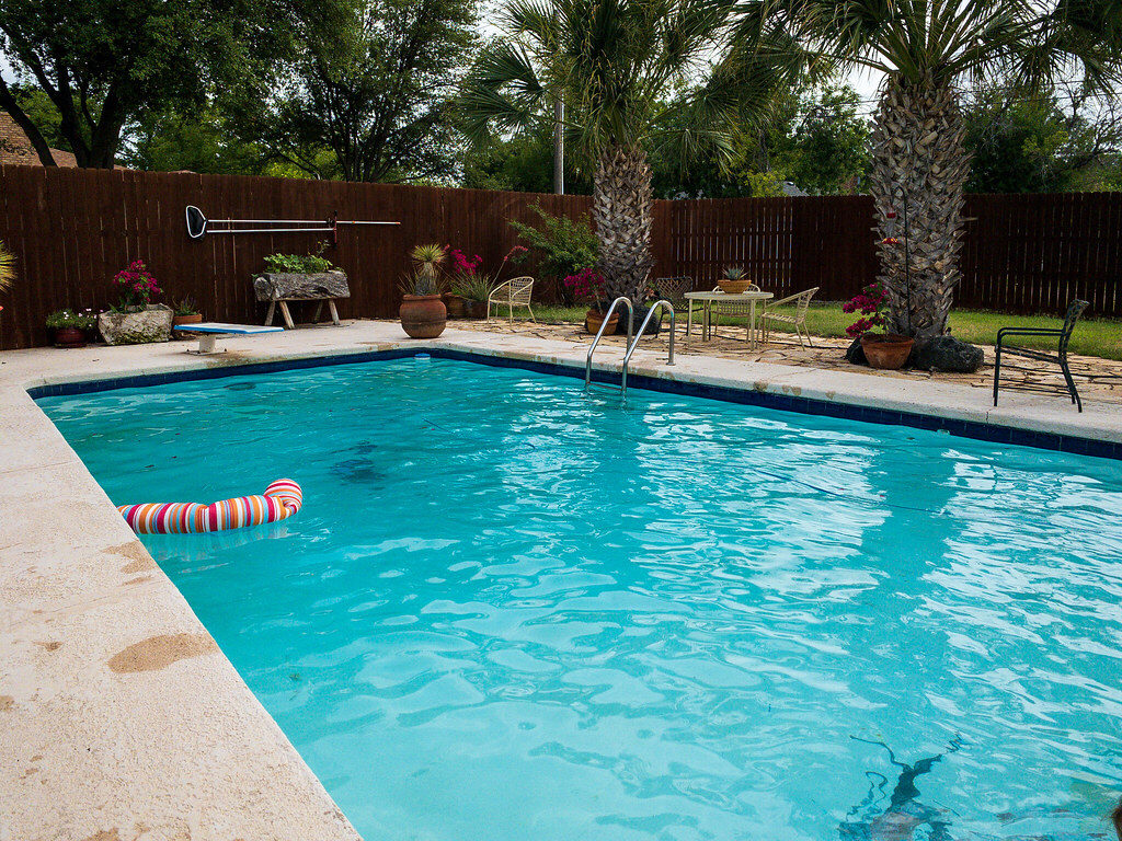 Backyard swimming pool kept swimmable through the season by a pool heat pump
