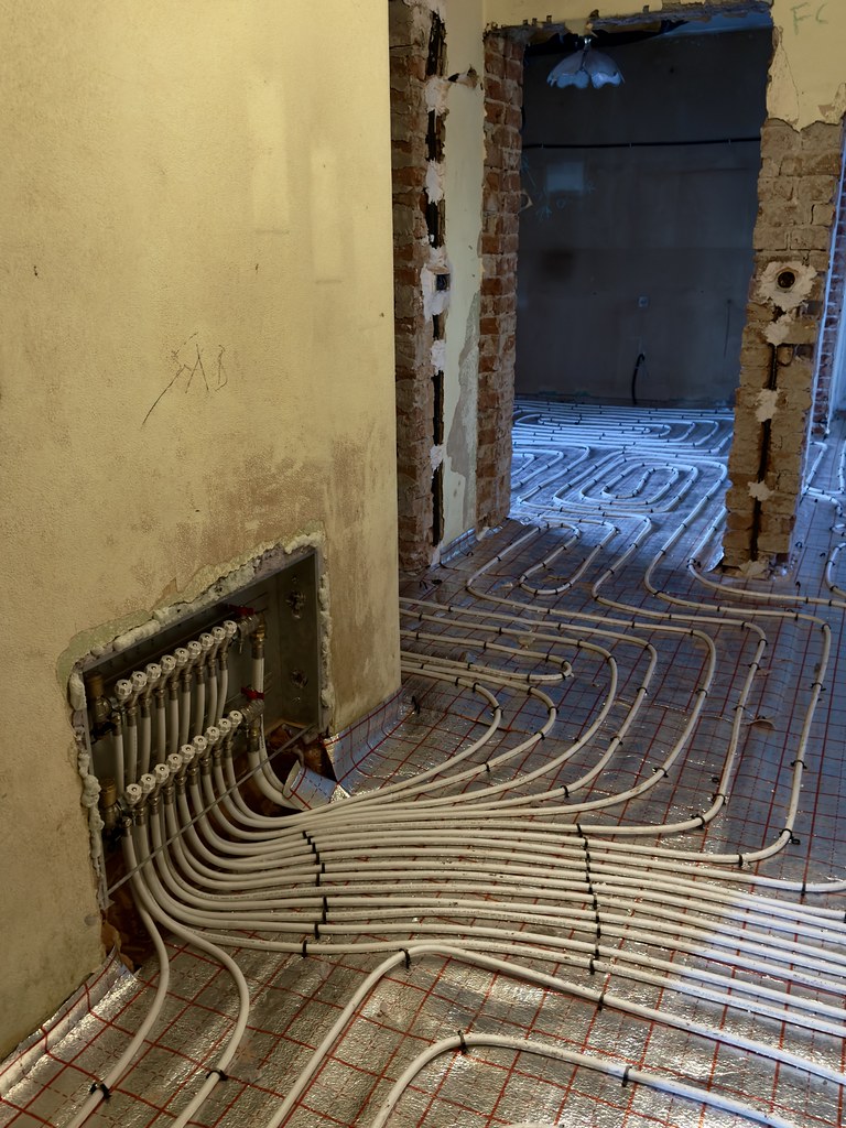 Underfloor heating pipe loops and manifold laid over insulation in a home renovation